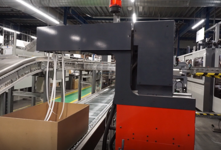 Print Feeder inserting a document into a box on a conveyor in a warehouse